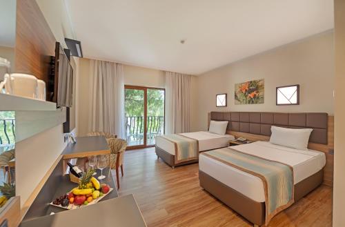 a hotel room with two beds and a table with a bowl of fruit at Kimeros Park Holiday Village - Ultra All Inc. Kids Concept in Kemer