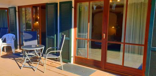 a patio with chairs and a table and a glass door at Alpenotel Rosenhof Ruhpolding, Wellness, Chiemgau Karte, Travelingo Bonus Programm in Ruhpolding