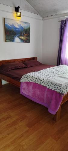 a bed in a room with a painting on the wall at K - Den Homestay in Kurseong
