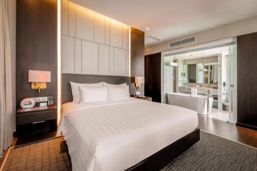a bedroom with a large white bed and a bathroom at New Orient Hotel Da Nang in Da Nang