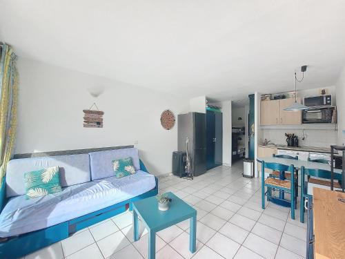 un salon avec un canapé bleu et une cuisine dans l'établissement V-Marin 06-Vieux Boucau Studio 4 personnes en rez de jardin avec piscine, à Vieux-Boucau-les-Bains