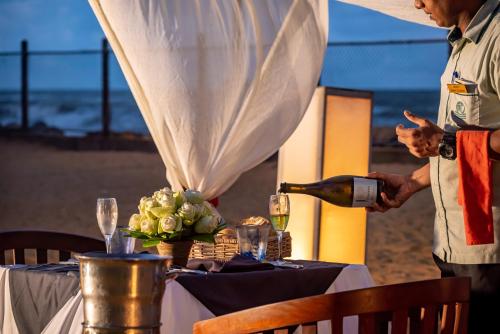 a man pouring a glass of wine at a table at Tangerine Beach Hotel in Kalutara