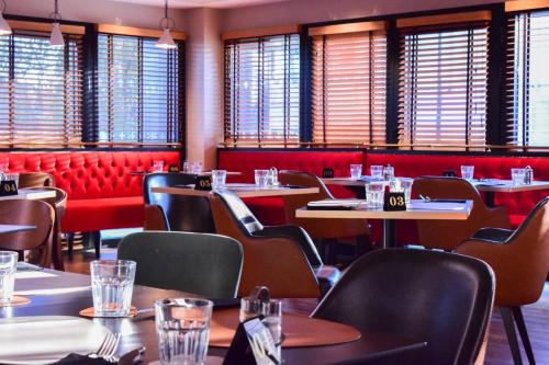 a restaurant with tables and chairs and windows at Best Western Plus Le Conquerant Rouen Nord in Bois-Guillaume