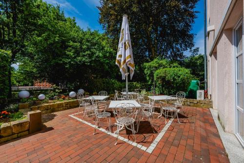 a patio with tables and chairs and an umbrella at Hotel am Schlosspark in Gotha