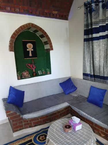 a room with a couch with blue pillows and a table at Nile Rose Hause in Al Karnak