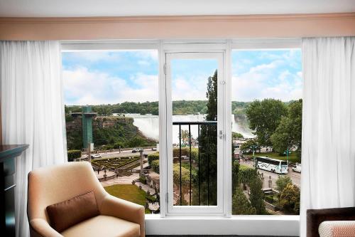 a room with a window with a chair and a view at Sheraton Fallsview Hotel in Niagara Falls