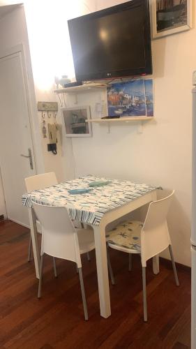 a dining room table with chairs and a tv on the wall at CASABARBARA lerici in Lerici
