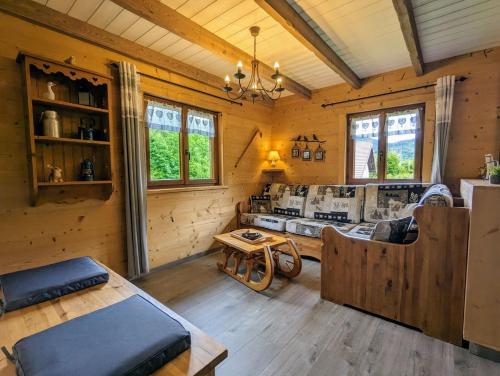 Cette cabane en rondins comprend un salon et une table. dans l'établissement Chalet Les Volets Rouges, à Cornimont
