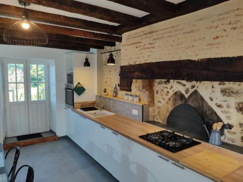 Il comprend une cuisine équipée d'une cuisinière. - un four au-dessus d'un mur en pierre dans l'établissement Grande maison d'hôtes proche Chenonceau, à Chisseaux