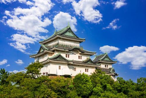 a tall castle with trees in front of a blue sky at Business Hotel Kawashima in Wakayama