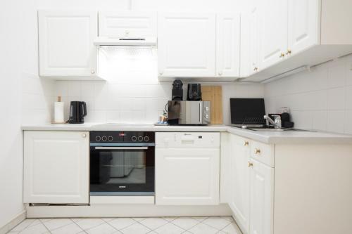 eine weiße Küche mit weißen Schränken und einem Backofen in der Unterkunft Cozy 1BR apartment near Opera - 24h self check-in in Wien