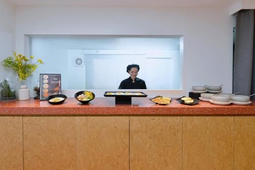a woman standing behind a counter with bowls of food at The Grass Serviced Suites in Pattaya Central