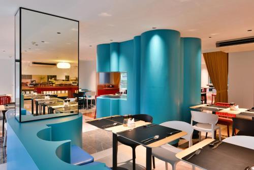 a restaurant with blue walls and tables and chairs at The Grass Serviced Suites in Pattaya