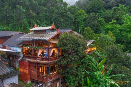 a house with people sitting on the balcony of it at Preanhuan Homestay in Mae On