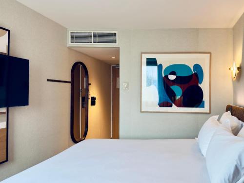 a bedroom with a large white bed and a painting at Golden Tulip Villepinte Roissy - Parc des Expositions in Roissy-en-France