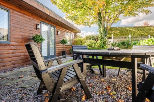 a picnic table and chairs in front of a cabin at The Lodge in Woodplumpton