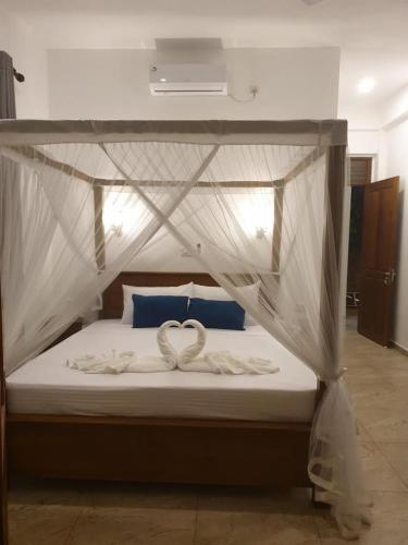 two white swans sitting on a bed with a canopy at CoCoSuRf House, Luxury among palms in Hikkaduwa