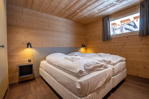 a bedroom with a large white bed in a wooden wall at Chalet Onno Henny in Bettmeralp