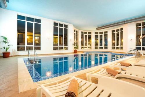 a swimming pool in a house with white chairs at Alpine Relax free spa & pool in Pamporovo