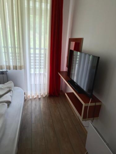 a living room with a flat screen tv on a stand at Alpine Relax free spa & pool in Pamporovo