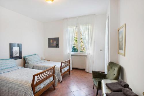 a bedroom with two beds and a chair and a window at Villa In Collina Vista Mare in Sanremo