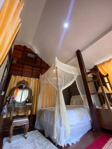 a bedroom with a canopy bed and a table at Preanhuan Homestay in Mae On