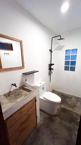 a white bathroom with a toilet and a sink at La Casita Catangnan in General Luna