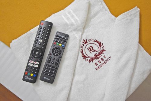 two remote controls sitting on top of a white shirt at Rubi Résidence in Puducherry