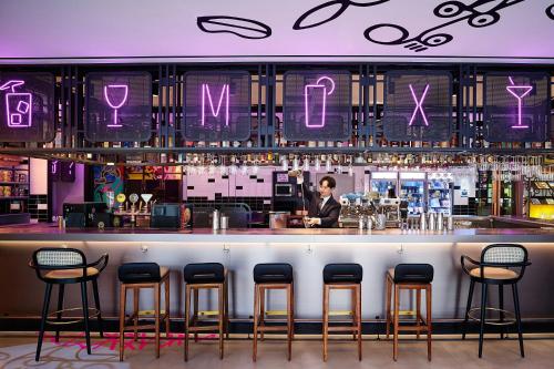 a bar with bar stools and a man behind the counter at Moxy Seoul Myeongdong in Seoul