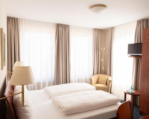 a hotel room with two beds and a chair at Restaurant & Hotel Kogge GmbH in Elsfleth