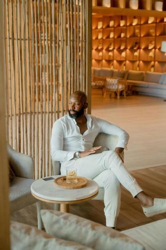 a man sitting in a chair next to a table at Santa Marta Marriott Resort Playa Dormida in Santa Marta