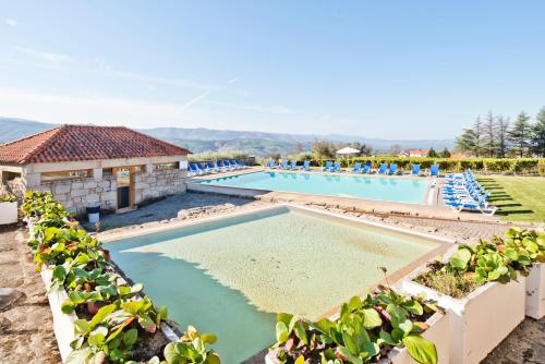 a pool at a resort with blue lounge chairs at Lam Hotel Convento do Desagravo in Oliveira do Hospital