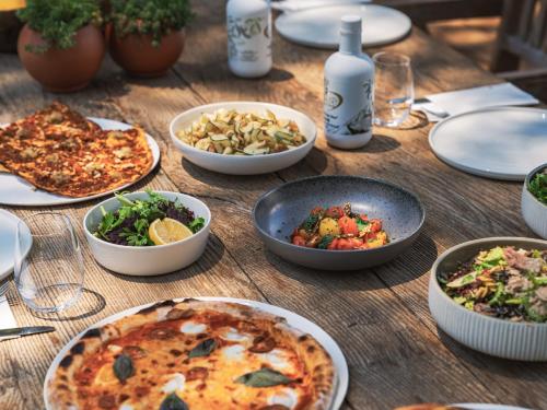 a wooden table topped with plates of food and pizza at Yazz Collective in Fethiye