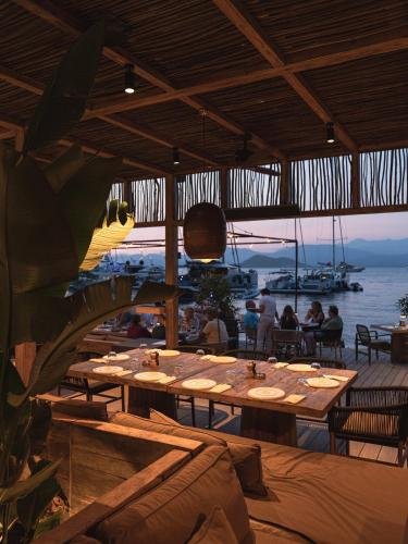 a restaurant with wooden tables and a view of the water at Yazz Collective in Fethiye