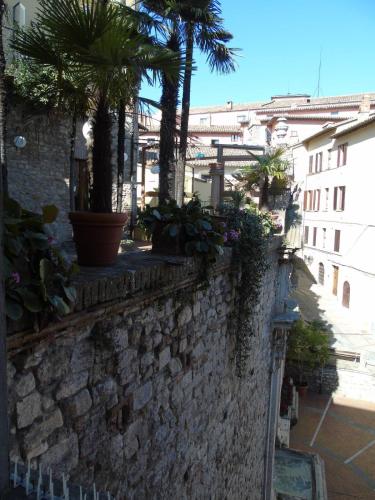 a stone wall with palm trees and plants on it at The Angela's House and large balcony on the square in Todi