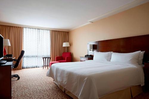 a hotel room with a large bed and a red chair at Stamford Marriott Hotel & Spa in Stamford