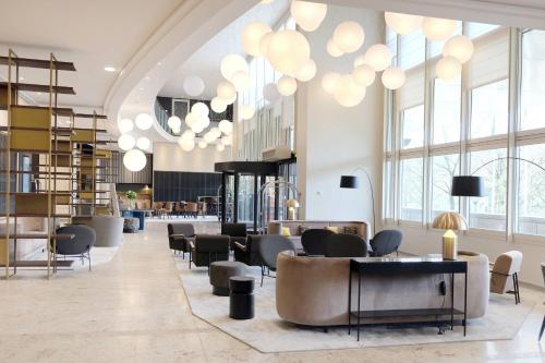 a lobby with chairs and tables and chandeliers at Lyon Marriott Hotel Cité Internationale in Lyon