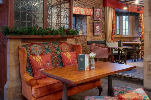 a room with a table and a couch and a table and a wooden table sidx at The Bell Inn, Stilton, Cambridgeshire - The Coaching Inn Group in Peterborough