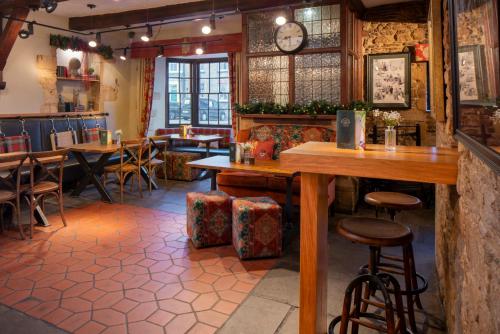 a restaurant with tables and chairs and a clock on the wall at The Bell Inn, Stilton, Cambridgeshire - The Coaching Inn Group in Peterborough