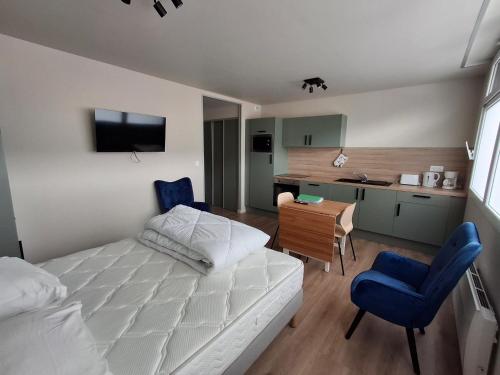 a bedroom with a bed and a desk and a kitchen at Les Gîtes du Moulin des Loups studios 3 et 6 in Saint-Amand-les-Eaux