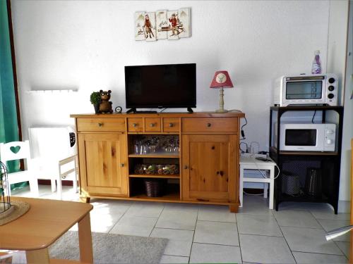 a living room with a television on a wooden cabinet at Appartement avec balcon au pied des pistes in Lélex