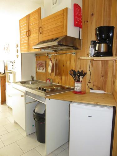 une cuisine avec des armoires en bois et un comptoir dans l'établissement Appartement avec balcon au pied des pistes, à Lélex