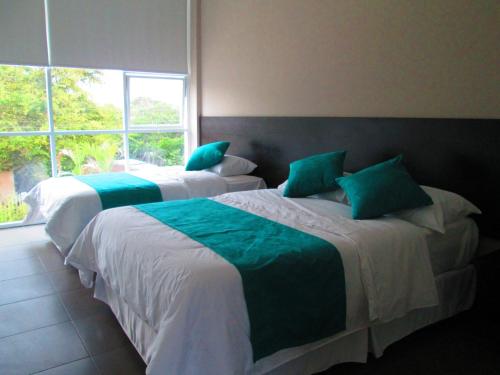 two beds in a room with a window at Ocean Blue Hotel in Olón