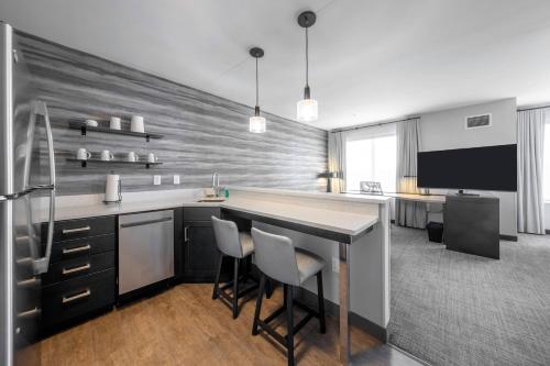 a kitchen with a bar with chairs and a tv at Residence Inn by Marriott Richmond at the Notch in Richmond