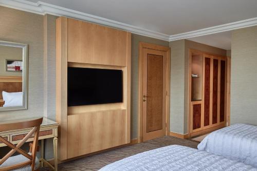 a bedroom with a bed and a desk with a television at Le Meridien Makkah in Makkah