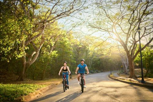 two people riding bikes down a road at The Westin Reserva Conchal, an All-Inclusive Golf Resort & Spa in Playa Conchal