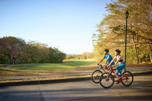 two people riding bikes down a road at The Westin Reserva Conchal, an All-Inclusive Golf Resort & Spa in Playa Conchal
