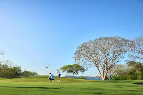 two people playing golf on a golf course at The Westin Reserva Conchal, an All-Inclusive Golf Resort & Spa in Playa Conchal