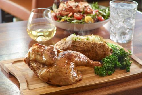 a wooden plate with meat and a salad and a glass of wine at Atlanta Airport Marriott Gateway in Atlanta