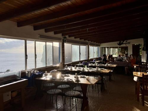 a dining room with tables and chairs and windows at Quinta Do Canavial in Velas